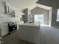 Bright kitchen featuring white cabinetry, stainless steel appliances, and a large center island with a black faucet at 825 Long Ave, Rocky Mount, NC 27801