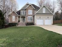 Charming two-story home featuring a stone facade and well-manicured lawn, plus a three car garage at 1404 Rhea Dr, Garner, NC 27529