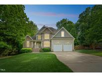 Charming two-story home with stone accents, well-manicured lawn, mature trees and a two car garage at 1404 Rhea Dr, Garner, NC 27529