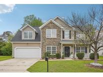 Charming two-story home featuring a stone facade, attached garage, and well-manicured lawn at 2223 Lazy River Dr, Raleigh, NC 27610