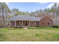 Charming brick home with a covered porch, mature landscaping, and a well-manicured lawn at 2411 Lynch Store Rd, Mebane, NC 27302