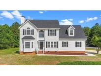 Charming two-story home with vinyl siding, a black roof, and manicured lawn on a sunny day at 1308 Aspen Falls Ct, Willow Springs, NC 27592
