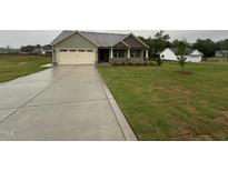Charming one-story home with a two-car garage and well-manicured lawn on a cloudy day at 141 Ruskin Dr, Smithfield, NC 27577