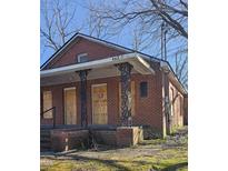 Red brick home with covered front porch, boarded up windows and overgrown landscaping at 1421 Blanton St, Rocky Mount, NC 27803