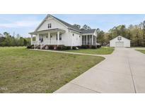 Charming two-story white farmhouse-style home with a welcoming front porch and manicured landscaping at 184 Mort Harris Rd, Louisburg, NC 27549