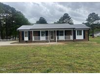 Charming brick home with a metal roof, covered porch, and freshly landscaped yard at 2130 Pearidge Rd, Angier, NC 27501