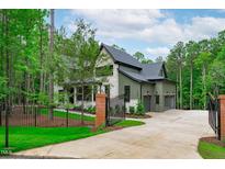 Stunning, luxury home with a gated entrance, stone accents, and lush landscaping at 2200 Paddstowe Main Way, Wake Forest, NC 27587
