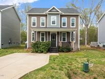 Two-story home featuring a well-maintained lawn, concrete driveway, and manicured shrubbery at 329 Chamberlain Dr, Clayton, NC 27527