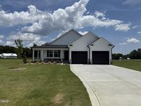 Charming, new construction home with a two car garage, concrete drive and manicured lawn on a sunny day at 47 Silver Ct, Smithfield, NC 27577