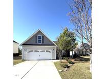 Charming home with a two-car garage, gray siding, and a manicured lawn on a bright, sunny day at 6320 Slopeside Ct, Raleigh, NC 27610