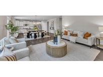 Open-concept living and dining area featuring hardwood floors and bright, white kitchen at 706 Fireball Ct, Knightdale, NC 27545