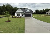 Charming single-Gathering home featuring a well-manicured lawn and a two-car garage, complete with a modern black door at 105 Tuskeegee Dr, Smithfield, NC 27577