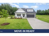 Charming home with white siding, stone accents, black garage doors, and a well-manicured lawn at 105 Tuskeegee Dr, Smithfield, NC 27577