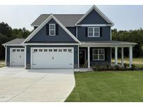 Charming two-story home features a three-car garage, covered porch, and blue siding at 106 Roma Gora Ct, Princeton, NC 27569