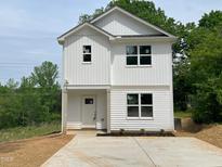 New two-story home with white siding, a concrete driveway, and landscaping with a harmonious blend of design and natural elements at 112 Remington Woods Dr, Wake Forest, NC 27587