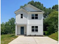 Charming two-story home with white siding, a blue front door, and a concrete driveway at 112 Remington Woods Dr, Wake Forest, NC 27587