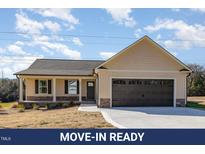 Charming single-story home featuring a two-car garage, covered porch, and neutral-tone siding at 122 Wilderness Trl, Smithfield, NC 27577