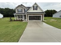 Two story home with a grey exterior, a large garage, and a well manicured front lawn at 125 Tuskeegee Dr, Smithfield, NC 27577