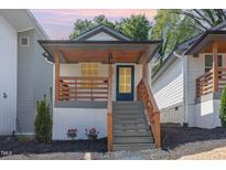Charming home featuring a covered porch with wooden railings, and well manicured landscaping, creating a welcoming curb appeal at 13 St Augustine, Raleigh, NC 27610