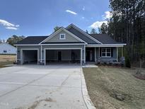 New construction home with three-car garage, black roof, light-green siding, and stone accents at 139 Red River Dr, Selma, NC 27576