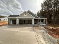 New construction home featuring a three-car garage, stone accents, and green siding at 139 Red River Dr, Selma, NC 27576
