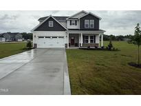Charming two-story home featuring a pristine lawn, neutral siding, and a spacious two-car garage at 141 Trescott St, Smithfield, NC 27577
