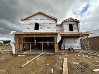 Exterior framing of a new two-story home under construction, showcasing the initial stages and design against a cloudy sky at 18 W Emily Gardens Dr, Selma, NC 27577