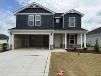 Two-story home boasts a dark blue facade, open garage and manicured front lawn at 18 W Emily Gardens Dr, Selma, NC 27576