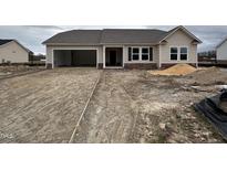 Charming single-story home featuring a two-car garage and stone accents, set in a new development neighborhood at 210 Maxwell Farm Ln, Selma, NC 27576