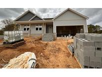 New home exterior featuring gray siding, dark shingles, and attached garage in a partially landscaped yard at 221 Tee Dr, Selma, NC 27576