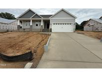Charming single-Gathering home showcasing a two-car garage and covered entryway, set against a backdrop of a cloudy sky at 221 Tee Dr, Selma, NC 27576