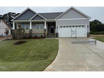 Charming home with a manicured lawn, inviting porch, and attached two-car garage at 221 Tee Dr, Selma, NC 27576