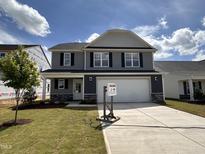Charming two-story home with a two-car garage, landscaped lawn and stone accents on the facade at 33 W Emily Gardens Dr, Selma, NC 27576