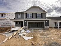 Two-story home featuring gray siding and black shutters, with an unfinished yard and a spacious, open garage at 33 W Emily Gardens Dr, Selma, NC 27576