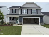 Two-story home featuring gray siding, black shutters, a spacious garage, and a well-manicured lawn at 33 W Emily Gardens Dr, Selma, NC 27576
