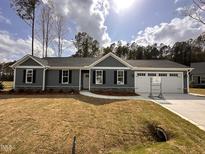 Charming one-story home with gray siding, black shutters, and a manicured lawn on a sunny day at 39 N Rowsham Pl, Smithfield, NC 27577