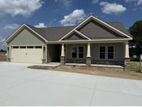 Charming single-story home featuring a covered porch with stone accents and a two-car garage at 56 Bailey-Boykin Rd, Selma, NC 27576