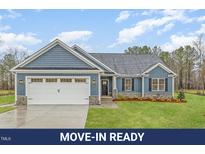 Charming home featuring a blue exterior, shingle accents, a two-car garage, and a well-maintained lawn at 613 Tuscany Cir, Princeton, NC 27569