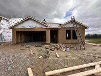 Under construction single-story home featuring an attached garage, exposed wood framing, and construction materials scattered around the yard at 8 W Emily Gardens Dr, Selma, NC 27577