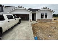 New construction, one-story home featuring light gray siding, stone accents, and an attached two car garage at 8 W Emily Gardens Dr, Selma, NC 27577