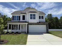 New two-story home with a white facade, black shutters, stone accents, and a spacious two-car garage at 83 W Emily Gardens Dr, Selma, NC 27576