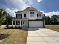 Beautiful two-story home with a covered porch, two-car garage, and a well-manicured front yard at 83 W Emily Gardens Dr, Selma, NC 27576