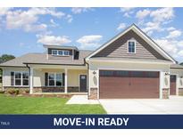 Charming single-Gathering home with a stone-accented facade, two-car garage, and well-manicured lawn at 87 Tee Dr, Selma, NC 27576