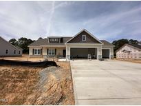 New construction home with attached three car garage and modern design elements at 87 Tee Dr, Selma, NC 27576