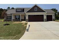 Charming home featuring tan siding, stone accents, a three-car garage, and manicured lawn at 87 Tee Dr, Selma, NC 27576