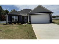 Charming single-Gathering home with a well-manicured lawn, a two-car garage, and a cozy front porch at 89 W Emily Gardens Dr, Selma, NC 27576