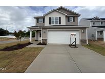 Two-story home featuring a wide driveway, a two-car garage, neutral siding, and manicured landscaping at 9 W Emily Gardens Dr, Selma, NC 27576