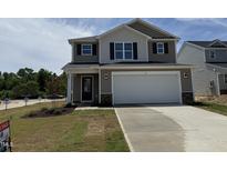 Charming two-story home featuring a two-car garage and well-manicured lawn on a sunny day at 9 W Emily Gardens Dr, Selma, NC 27576
