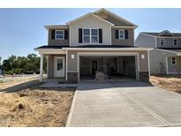 Two-story home with a large garage and neutral colored siding and stone accents at the garage entry at 9 W Emily Gardens Dr, Selma, NC 27576