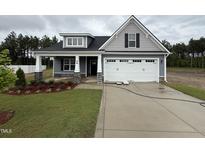 Charming two-story home with landscaped yard, attached garage, and welcoming front porch at 98 Laramie Ln, Selma, NC 27576